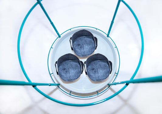 Top-down view of three 3-gallon fabric grow bags evenly spaced on the Bloom Carousel’s 22-inch rotating tray, framed by teal steel ring and vertical supports.