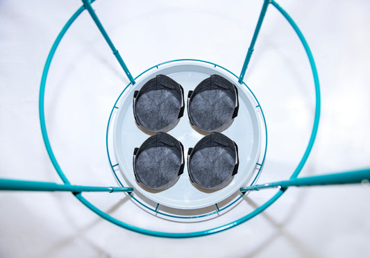Top-down view of four 1-gallon fabric grow bags evenly spaced on the Bloom Carousel’s 22-inch rotating tray, framed by teal steel ring and uprights.
